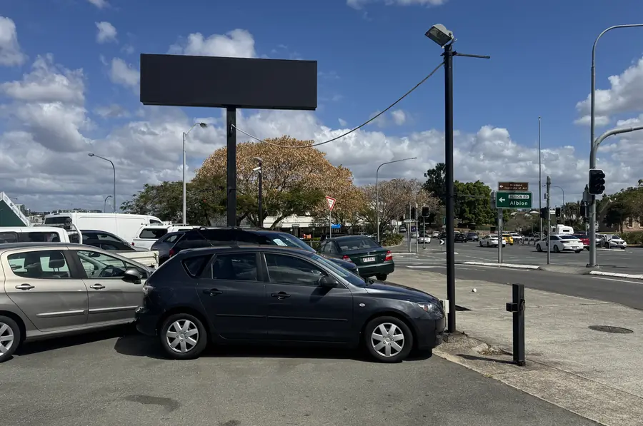 The corner of the yard at the traffic lights, under the tall sign